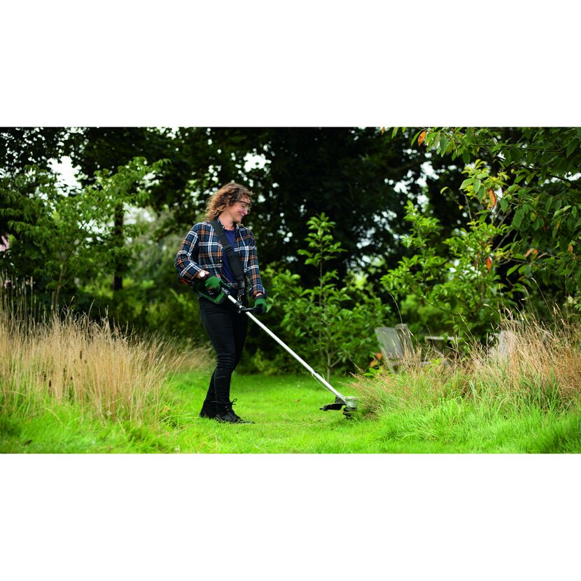 Person mäht hohes Gras mit Rasentrimmer
