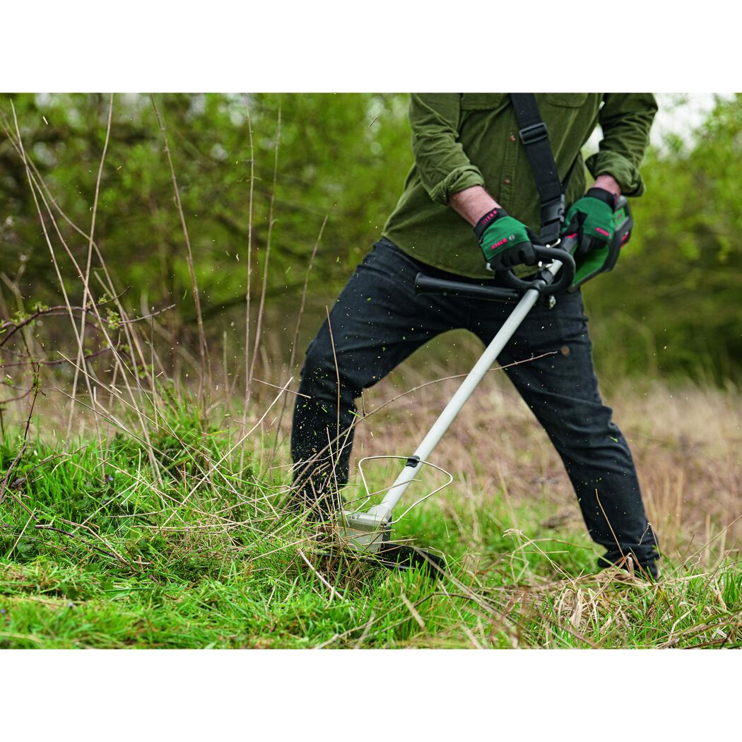 Person mäht mit Akku-Rasentrimmer Gras