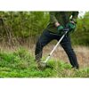 Person mäht hohes Gras mit einem Rasentrimmer.