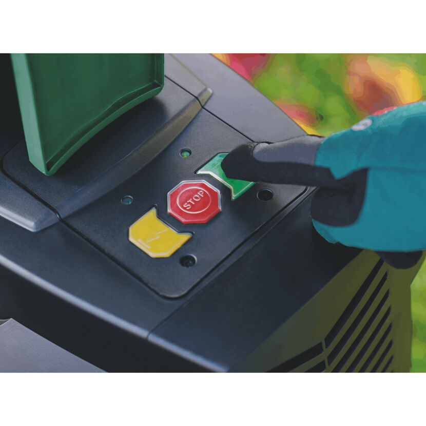 Person drückt den roten Stoppknopf an einem Gartenhäcksler.