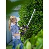 Person schneidet eine Hecke mit einer elektrischen Heckenschere.