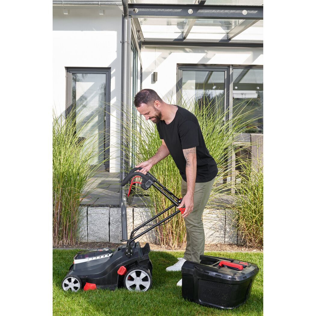 Person klappt den Griff eines Akku-Rasenmähers zusammen.