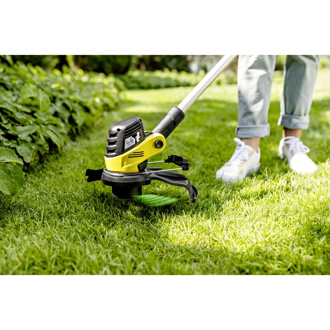 Person kürzt Gras mit Rasentrimmer