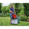 Person befüllt Häcksler mit Gartenabfällen