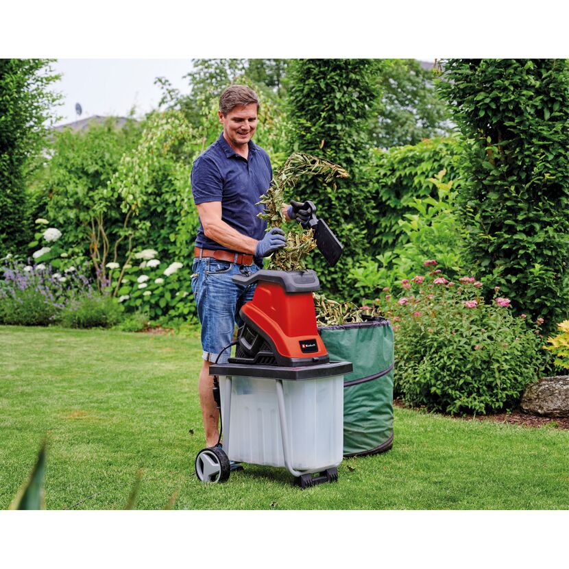 Person befüllt Häcksler mit Gartenabfällen