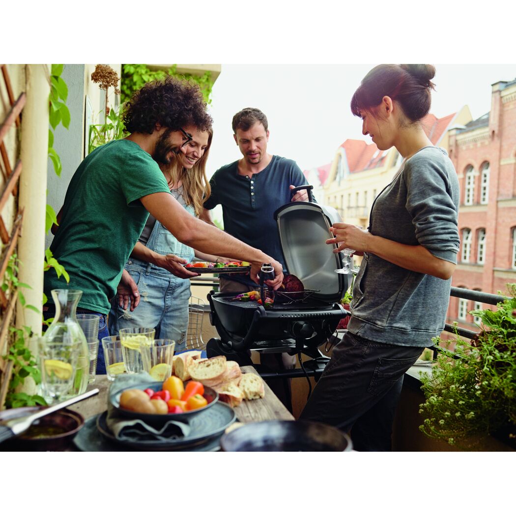 Personen grillen auf dem Balkon mit einem Elektrogrill.