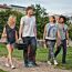 Vier Personen tragen einen Gasgrill Go-Anywhere und Picknickutensilien.