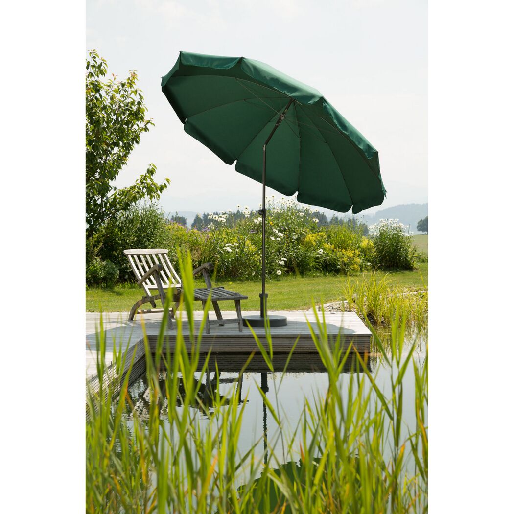 Grüner Sonnenschirm neben einem Liegestuhl am Teich