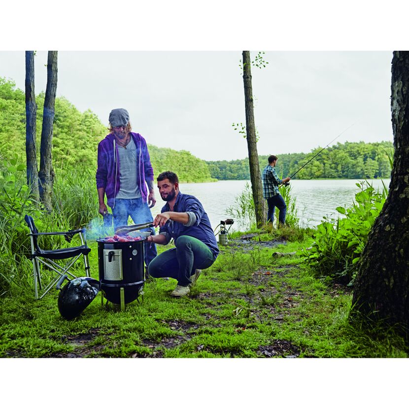 Personen grillen am See mit dem Smokey Mountain Cooker.