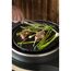 Person grillt Lammkoteletts und Spargel mit einer Zange.