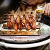 Hähnchenschenkel im Hähnchenrack auf einem Grill