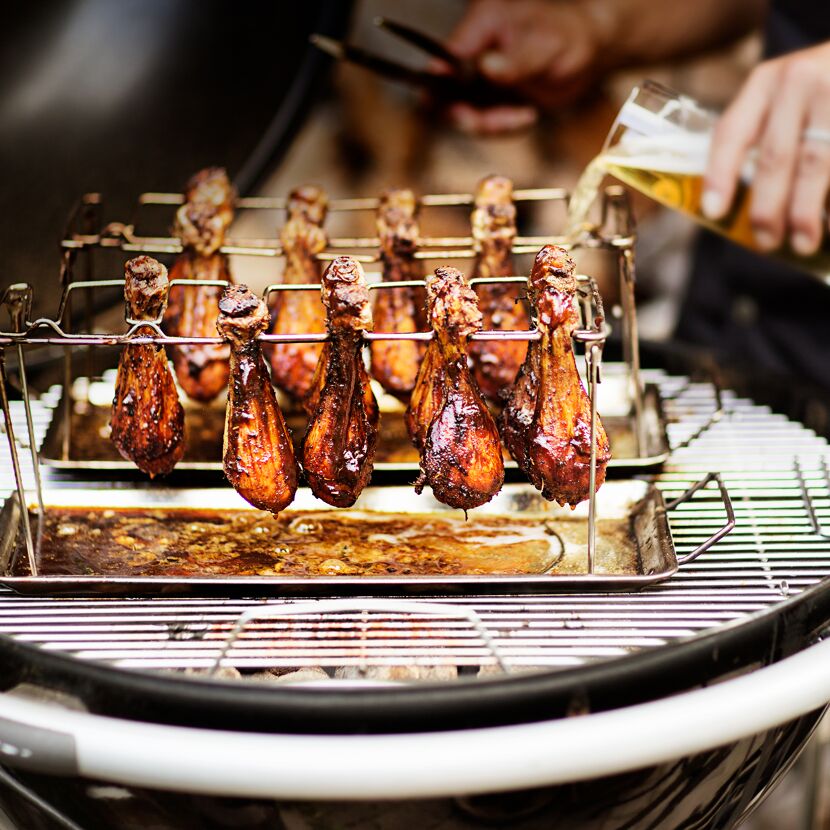 Hähnchenschenkel im Hähnchenrack auf einem Grill