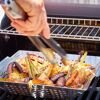 Person grillt Gemüse mit Grillzange in Grillpfanne