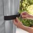 Person schließt Klettverschluss an einer Weber Grill-Abdeckhaube