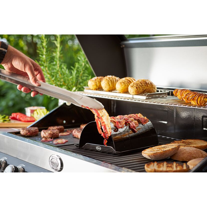 Person grillt Speck mit Speckgriller auf einem Gasgrill.