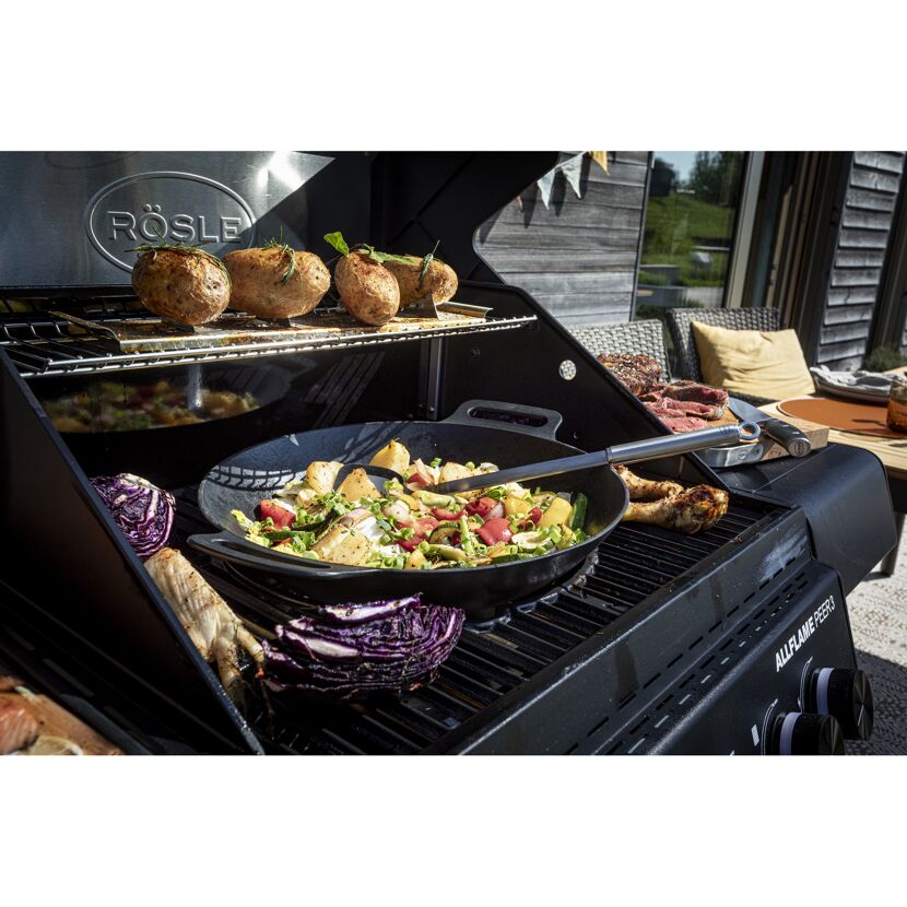 Gemüse und Kartoffeln werden auf einem Grill zubereitet.