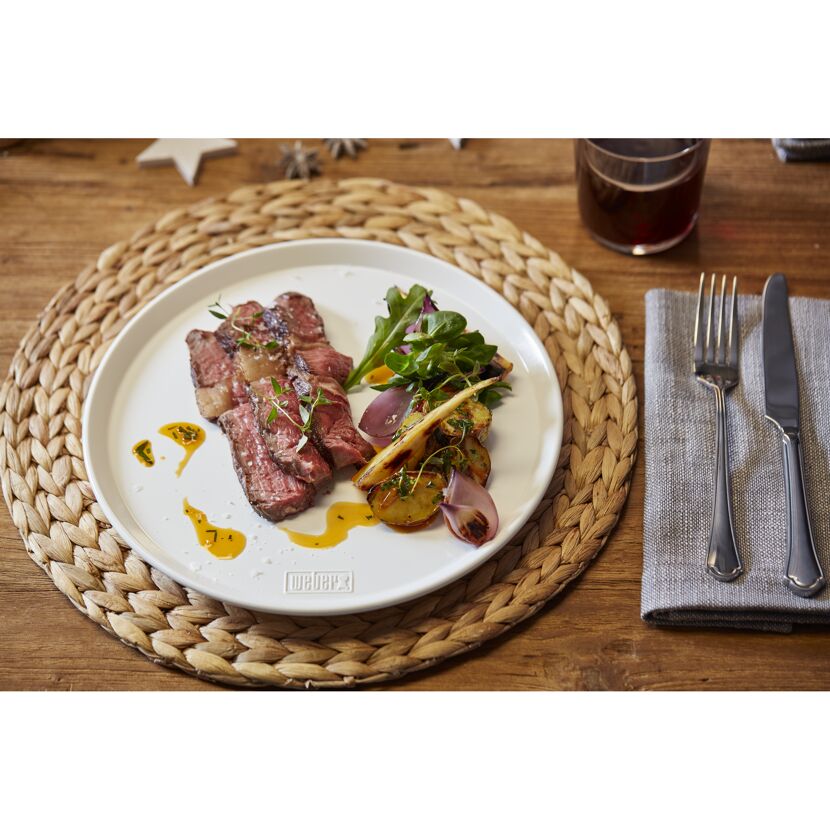 Gegrilltes Steak mit gebratenem Gemüse auf einem weißen Teller.