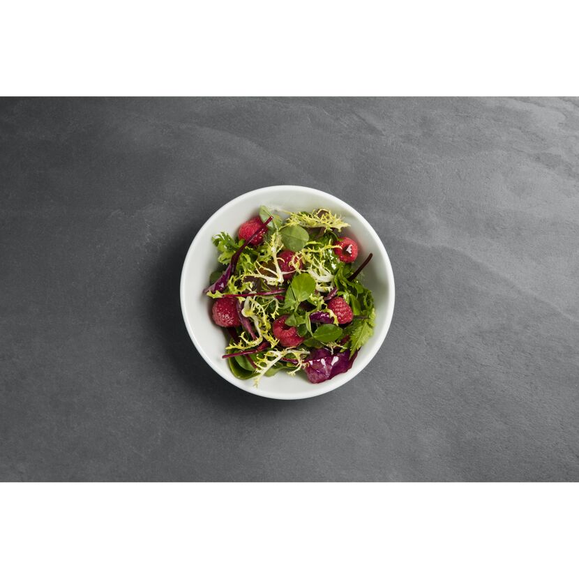 Grüner Salat mit Himbeeren in weißer Schüssel