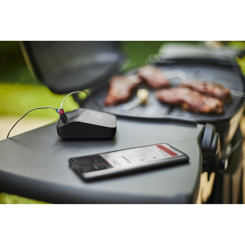 Weber Connect Smart Grilling Hub neben einem Grill und Smartphone