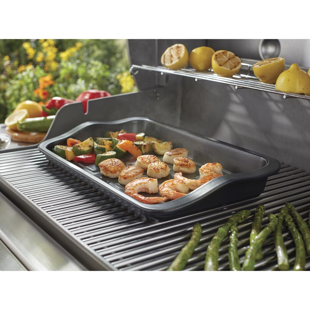 Garnelen, Jakobsmuscheln und Gemüse werden auf einer Grillplatte gegrillt.