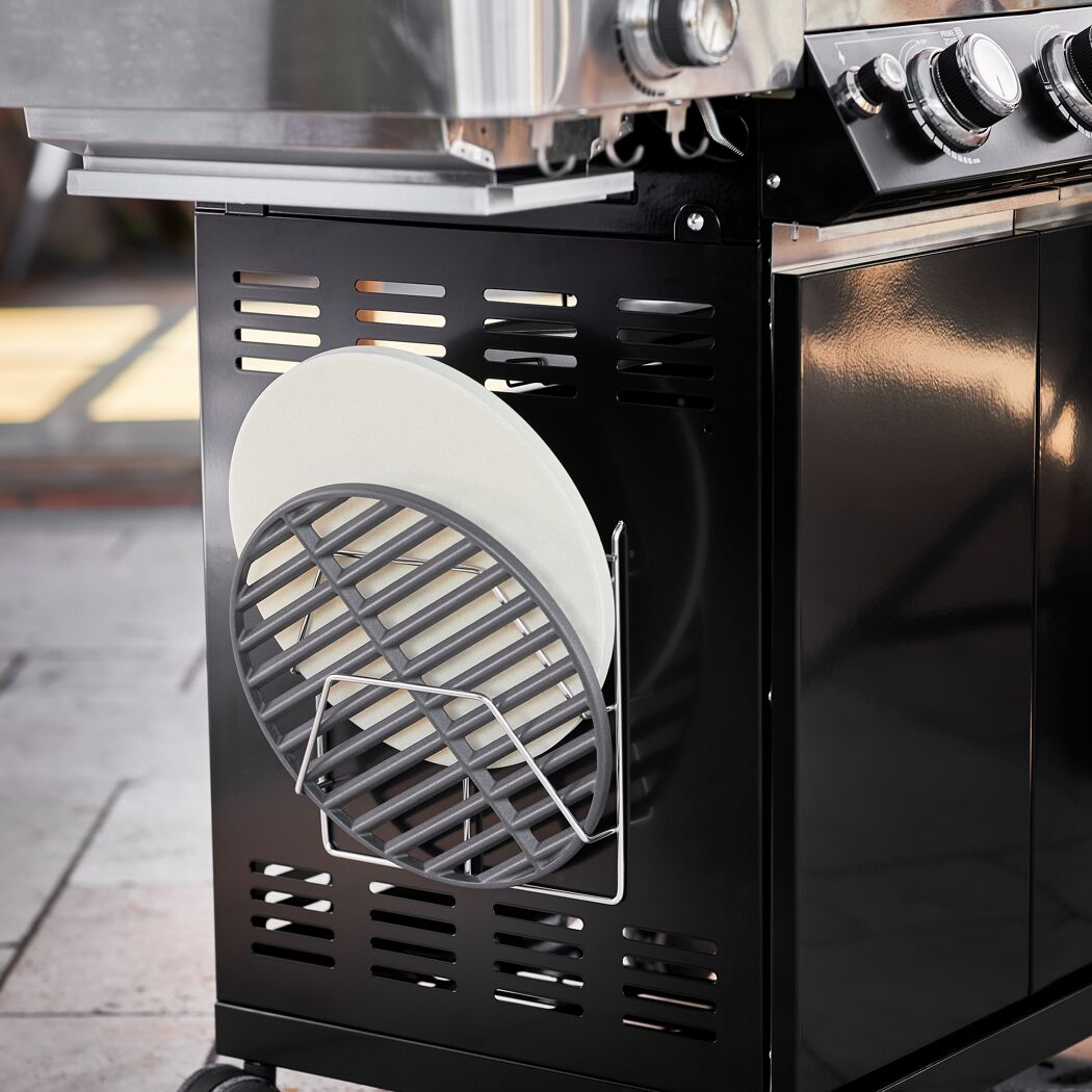 Grillrost und Pizzastein im Unterschrank eines Gasgrills