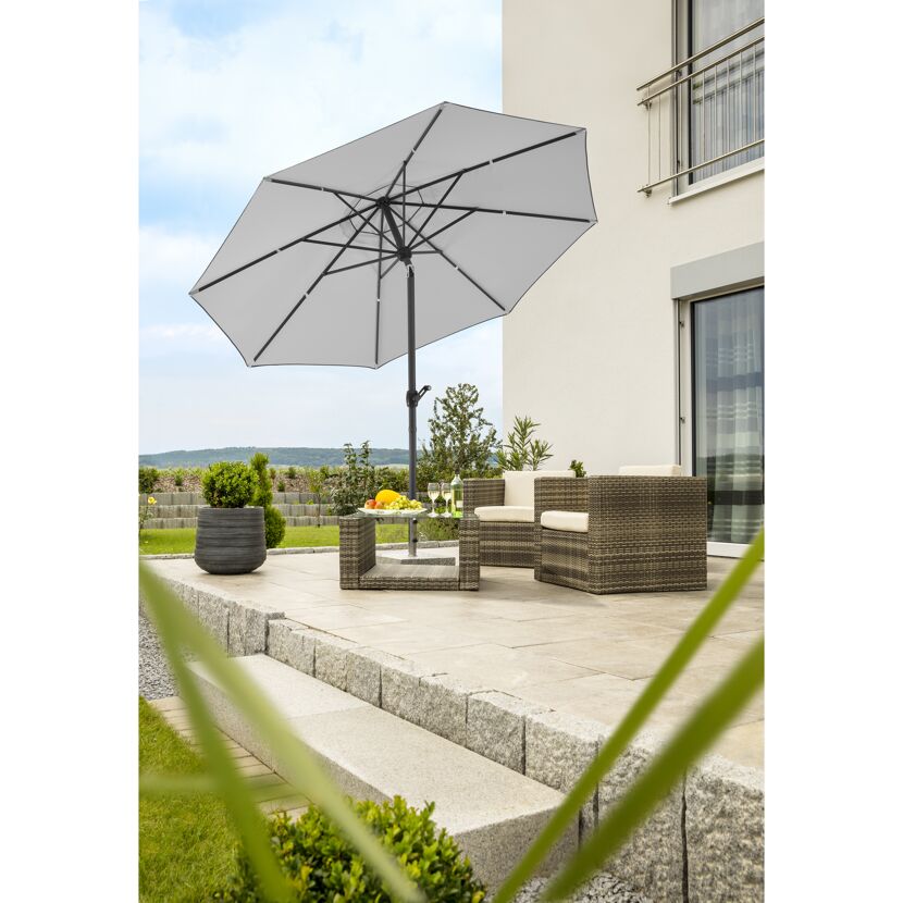 Terrasse mit Sonnenschirm, Lounge-Möbeln und Tisch.