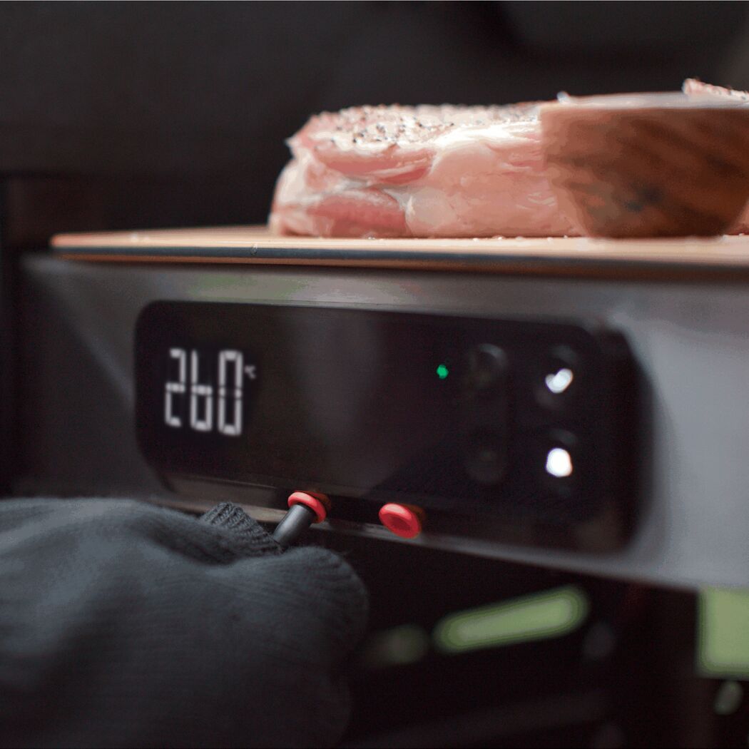 Person grillt Fleisch auf einem Gasgrill.
