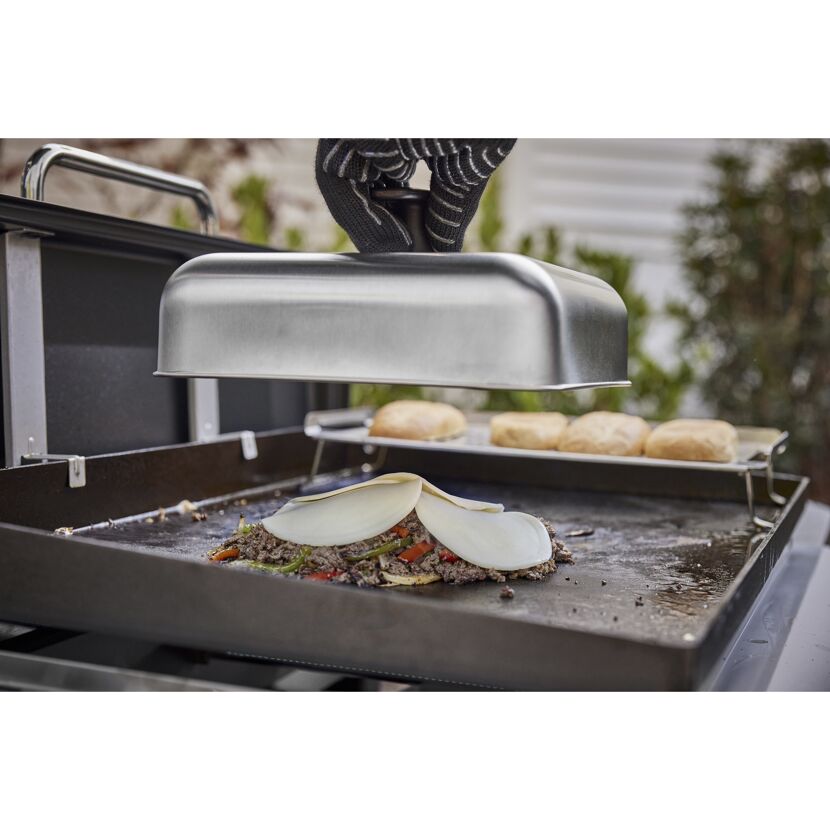 Person verwendet Grillhaube zum Schmelzen von Käse