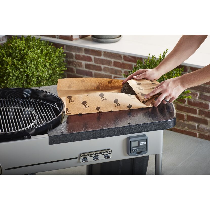 Person legt Weber Butcher Papier auf einen Grill.