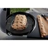 Fleisch wird in Backpapier auf einem Grill gegart.