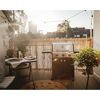 Gasgrill auf einem Balkon mit Tisch und Stühlen.