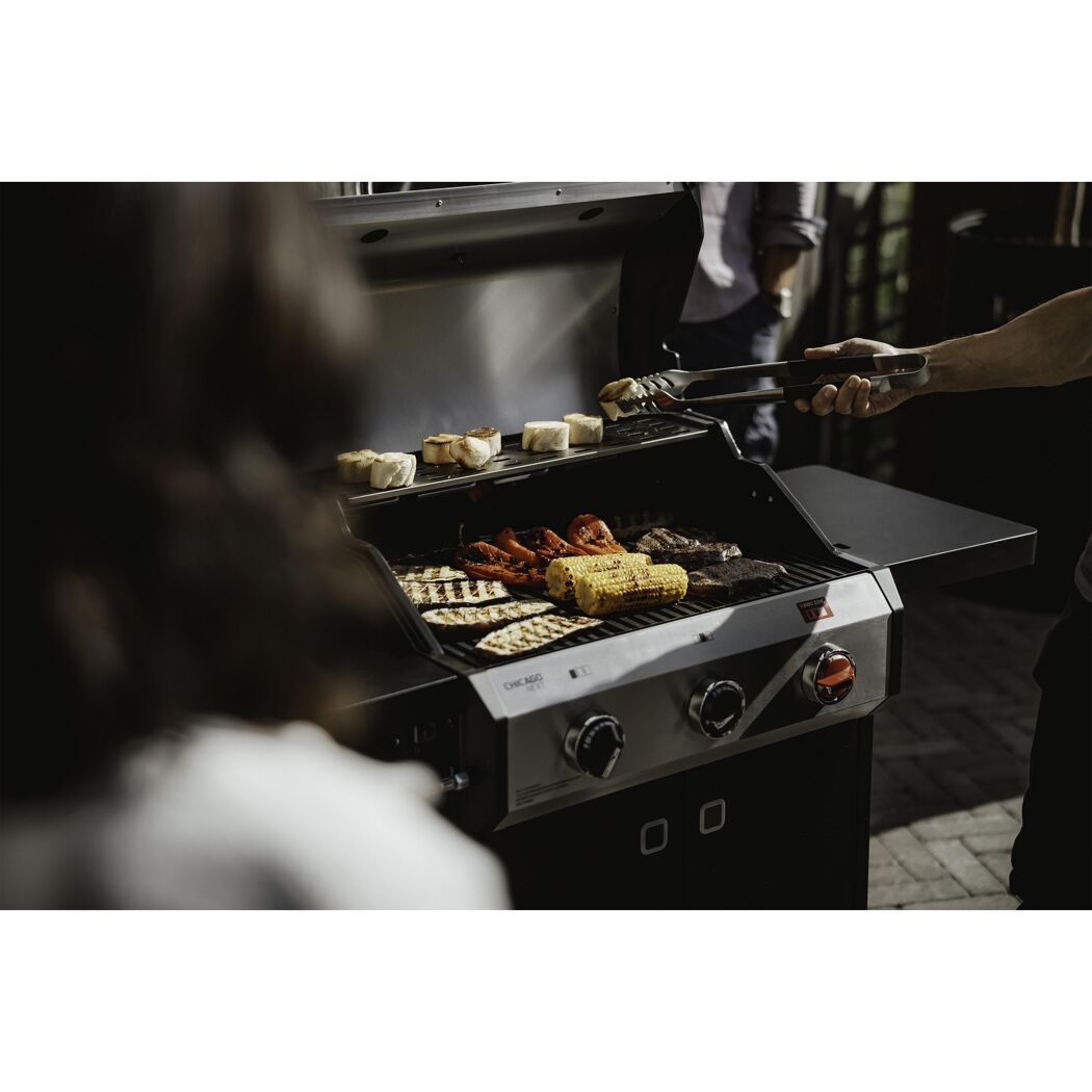 Person grillt Gemüse, Steaks und Baguette auf einem Gasgrill
