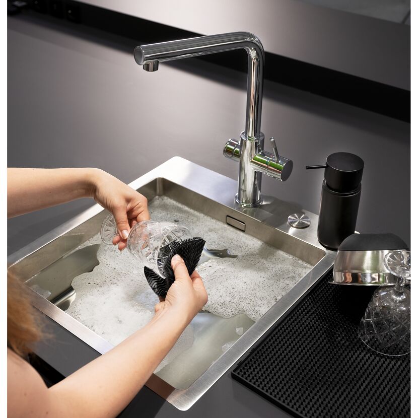 Person spült Glas in Spüle mit Schwamm