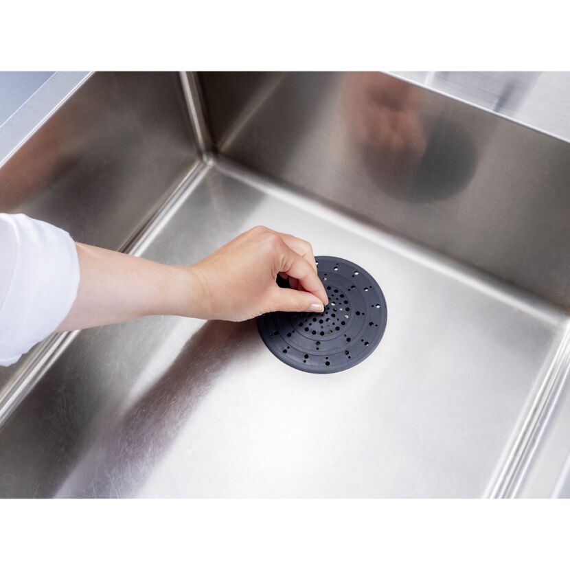 Hand legt Abfluss-Sieb in Spüle