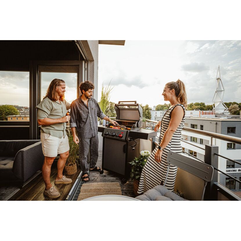 Personen beim Grillen auf einem Balkon.