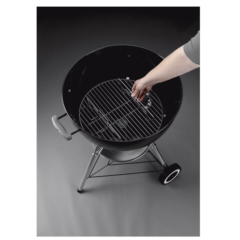 Person legt Kohlerost in Holzkohlegrill