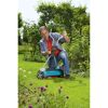 Person kniet auf einem Rasen und stellt einen GARDENA Spindelmäher ein.