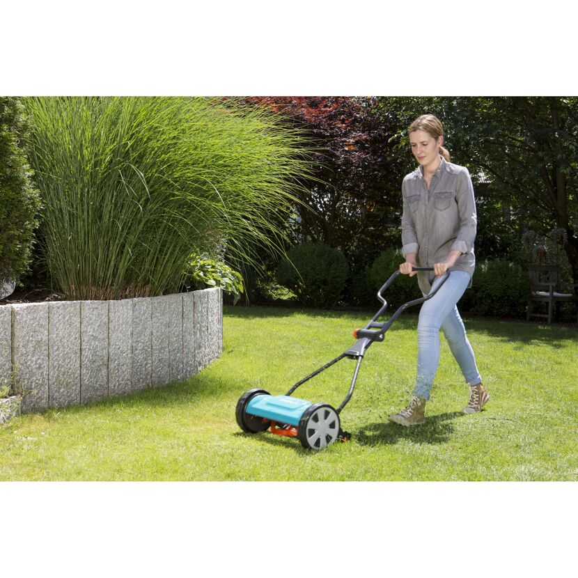 Person mäht Rasen mit Spindelmäher.