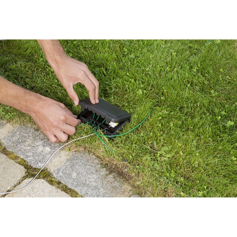 Person schließt Kabel im Garten an.