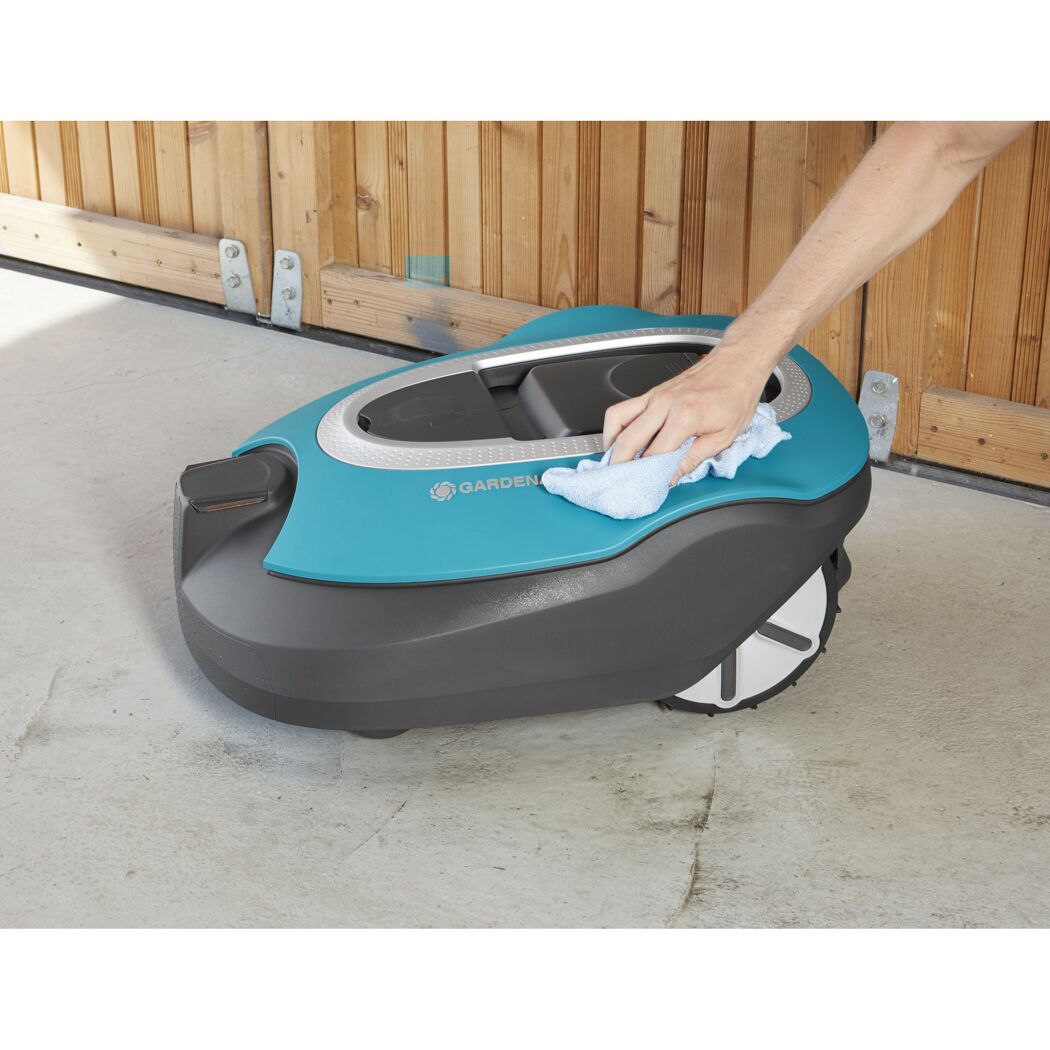 Person reinigt Mähroboter mit einem Tuch