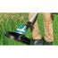 Person verwendet Elektro-Rasentrimmer im Gras.