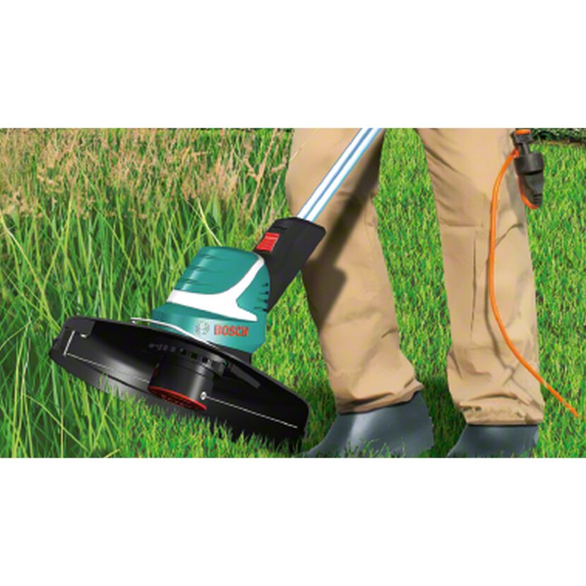 Person verwendet Elektro-Rasentrimmer im Gras.