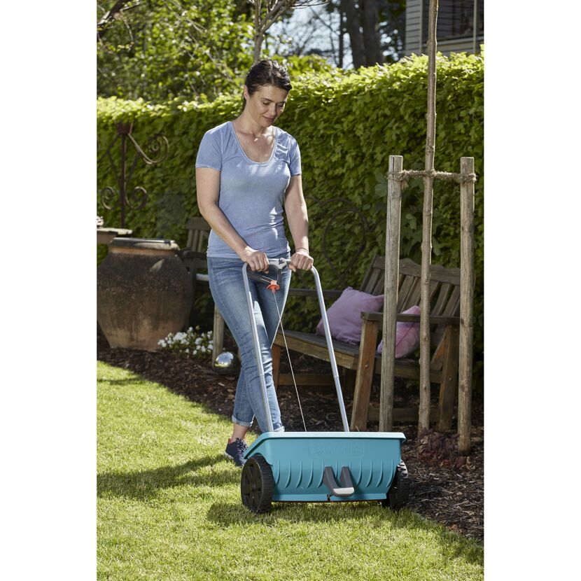 Person verwendet einen GARDENA Streuwagen.