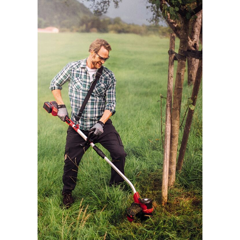 Person mäht Gras mit Akku-Rasentrimmer.