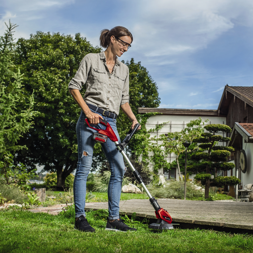 Person verwendet einen Akku-Rasentrimmer.