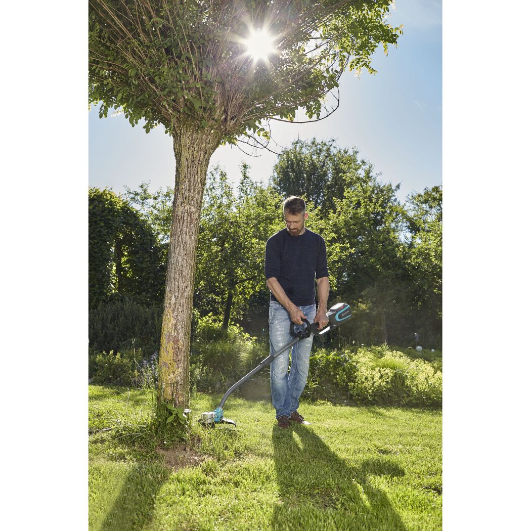 Person mäht Rasen mit Akku-Trimmer