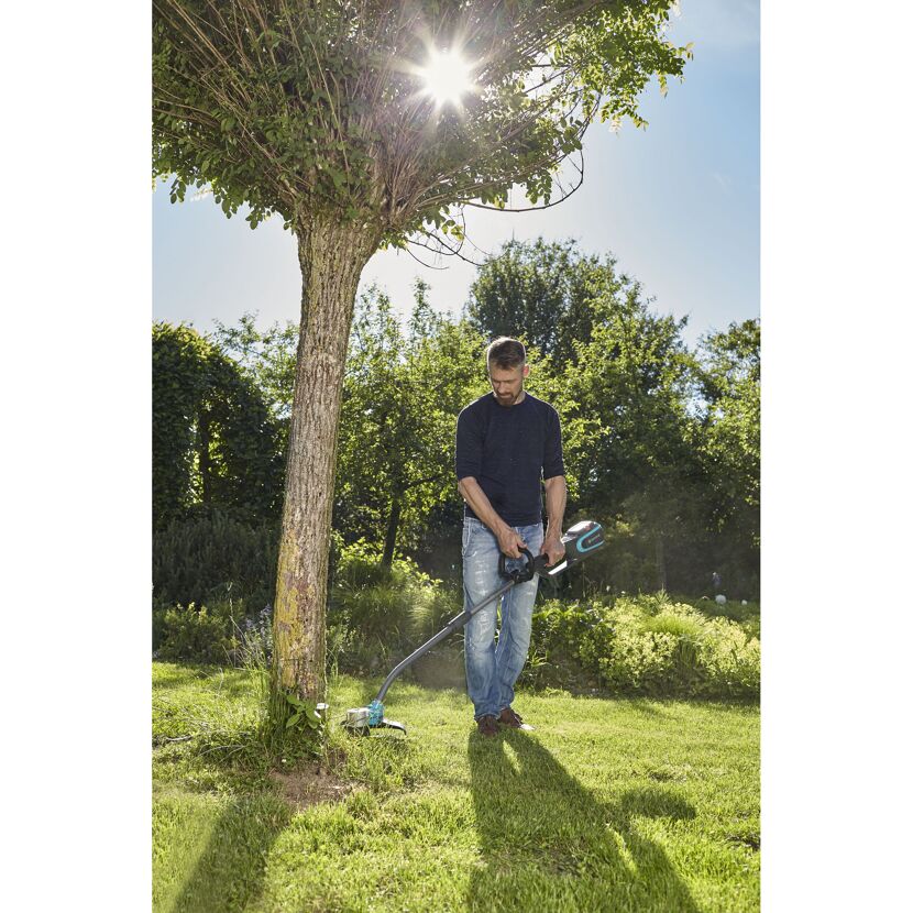 Person mäht Rasen mit Akku-Trimmer