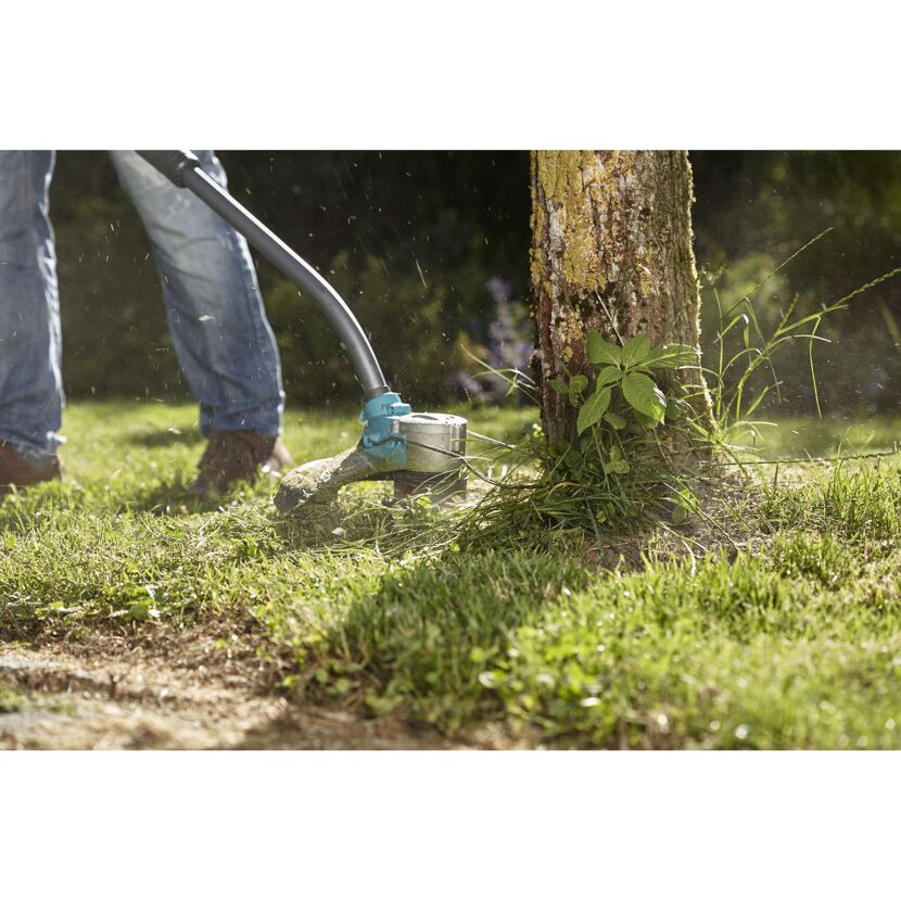 Person kürzt Gras mit Akku-Trimmer