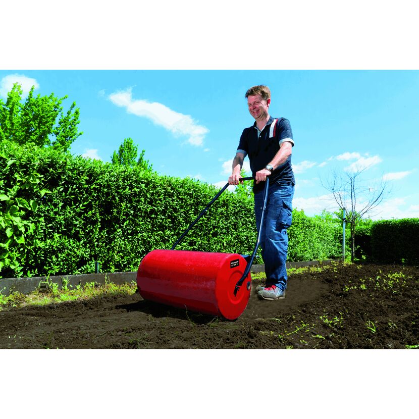 Person verwendet Rasenwalze im Garten