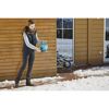 Person streut mit blauem Handstreuer Schnee.